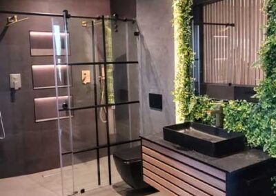 Modern bathroom with frameless glass shower panels and a plant-covered feature wall