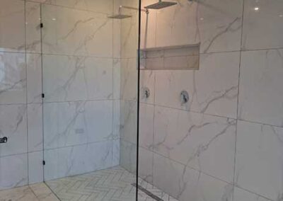 Frameless glass walk-in shower with marble-effect tiles and rainfall showerhead