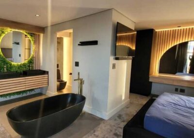 Modern bedroom and bathroom suite with freestanding bath and illuminated mirrors