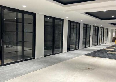 Black-framed glass partitions lining a spacious modern interior corridor