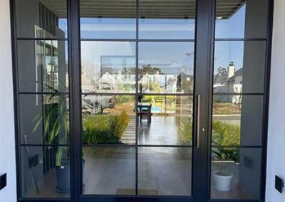Black-framed glass entrance with sidelights and a modern grid design.