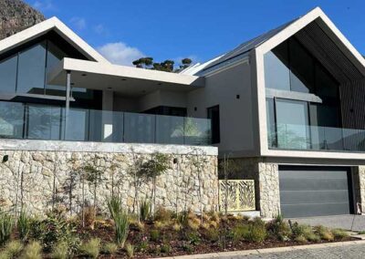 Modern hillside home with expansive glass façades and frameless balcony balustrades